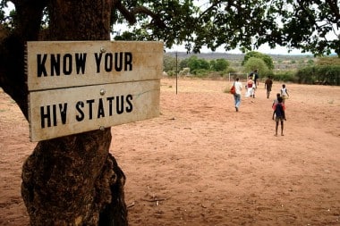 sign on tree in Zambia saying "Know Your H.I.V. Status"
