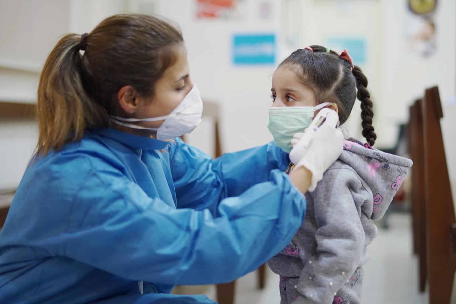 Medical volunteer putting a mask on a child.