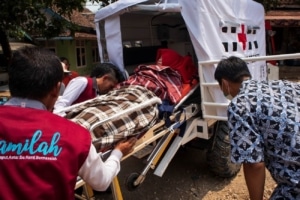 Mini mobile ambulance in Indonesia carried by three people with an expecting mother inside.