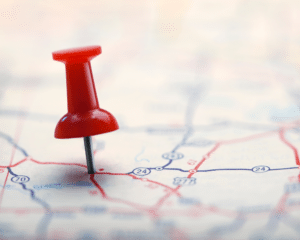 A red push pin on a generic road map