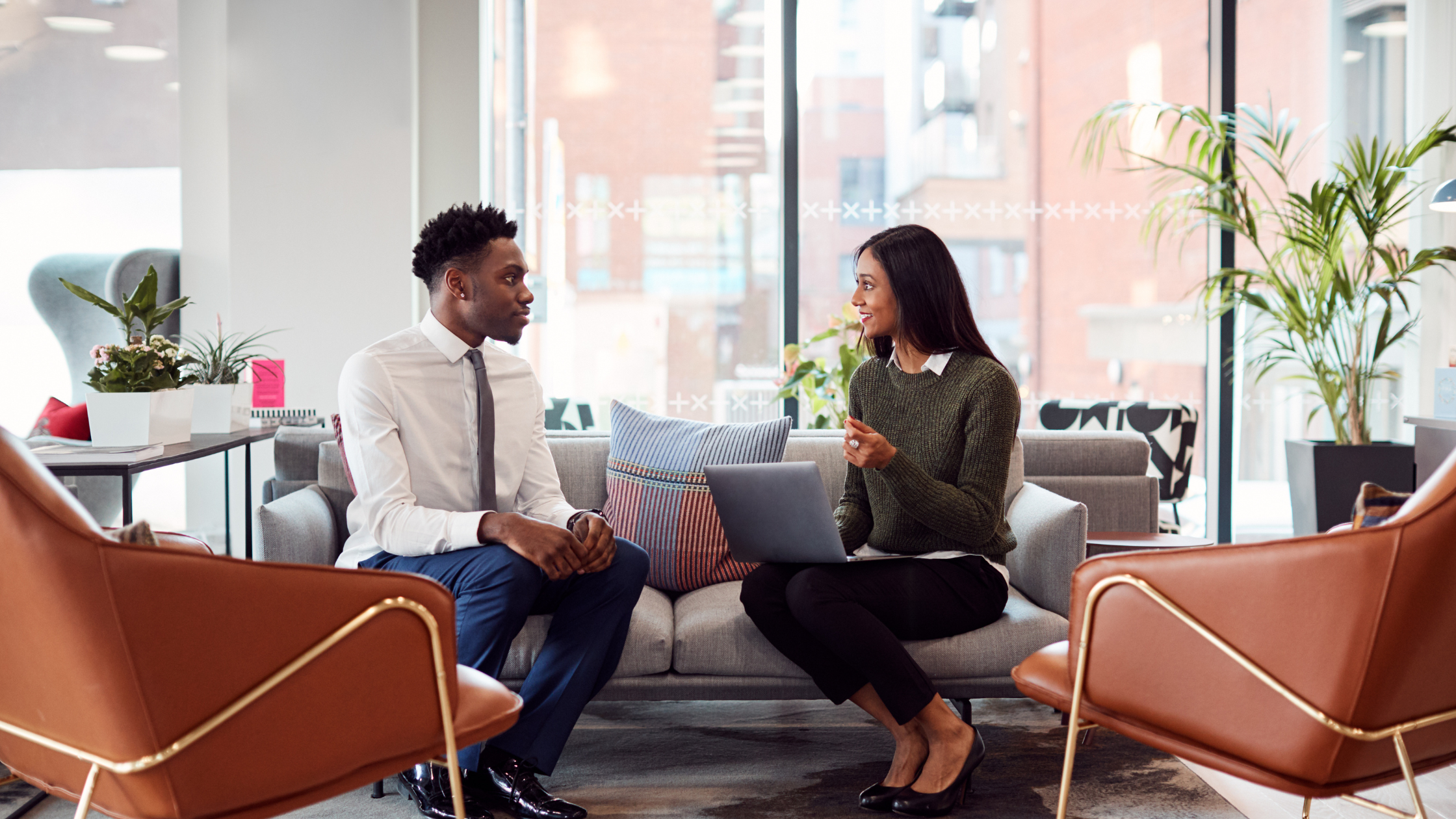 Businesswoman Interviewing Male Job Candidate In Seating Area Of Modern Office