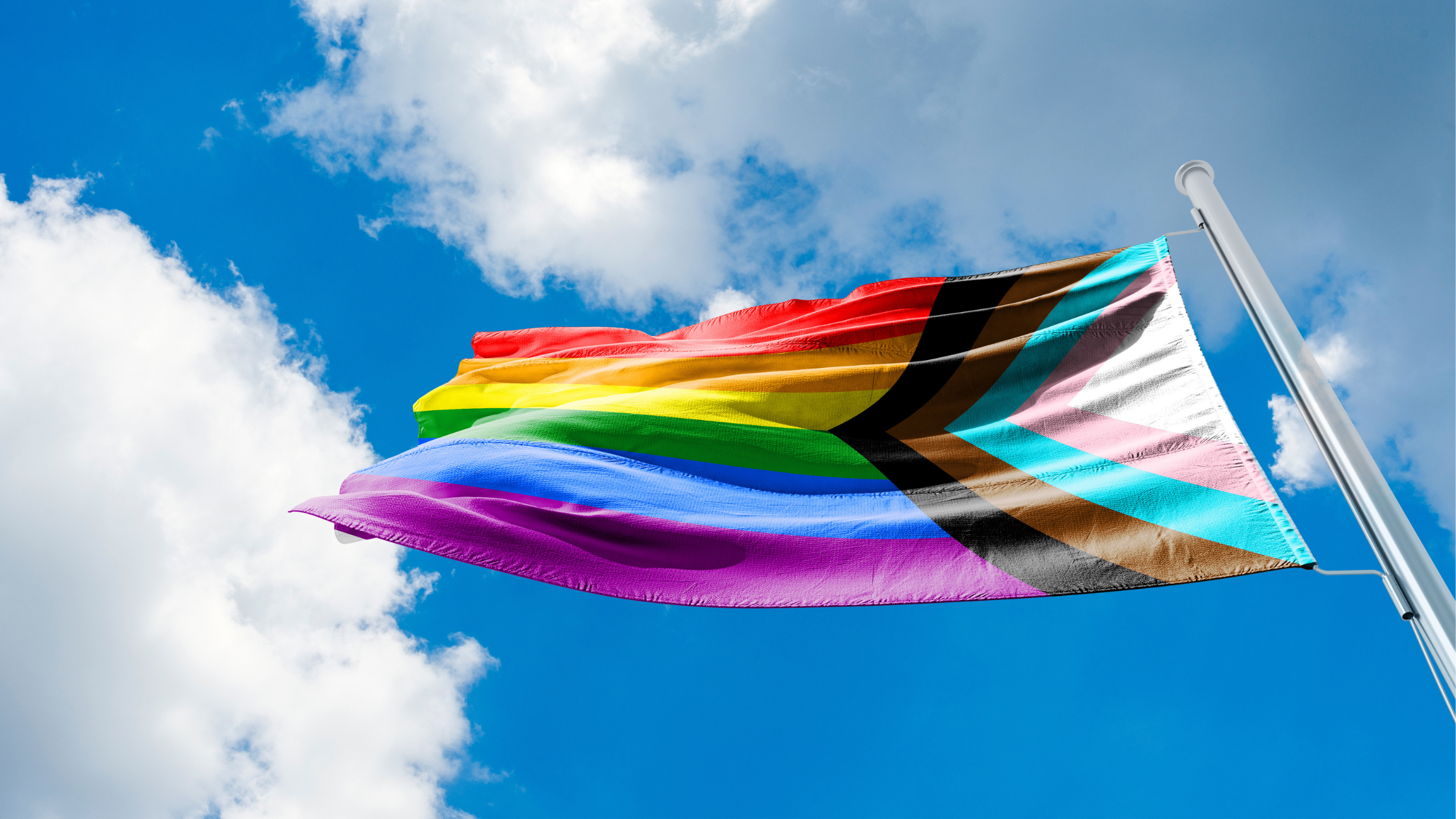 How can international development organizations actively support LGBTQ+ employees and workers?