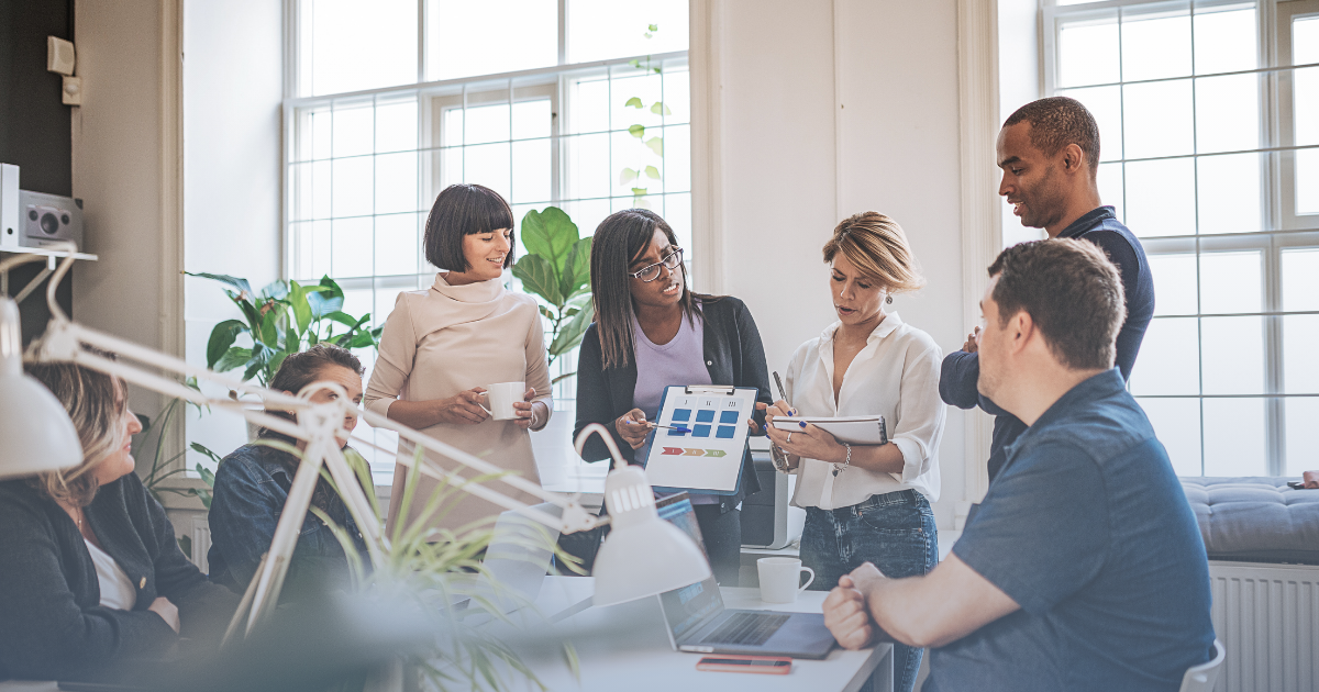 Photo showing an office with people around a table looking at a chart.